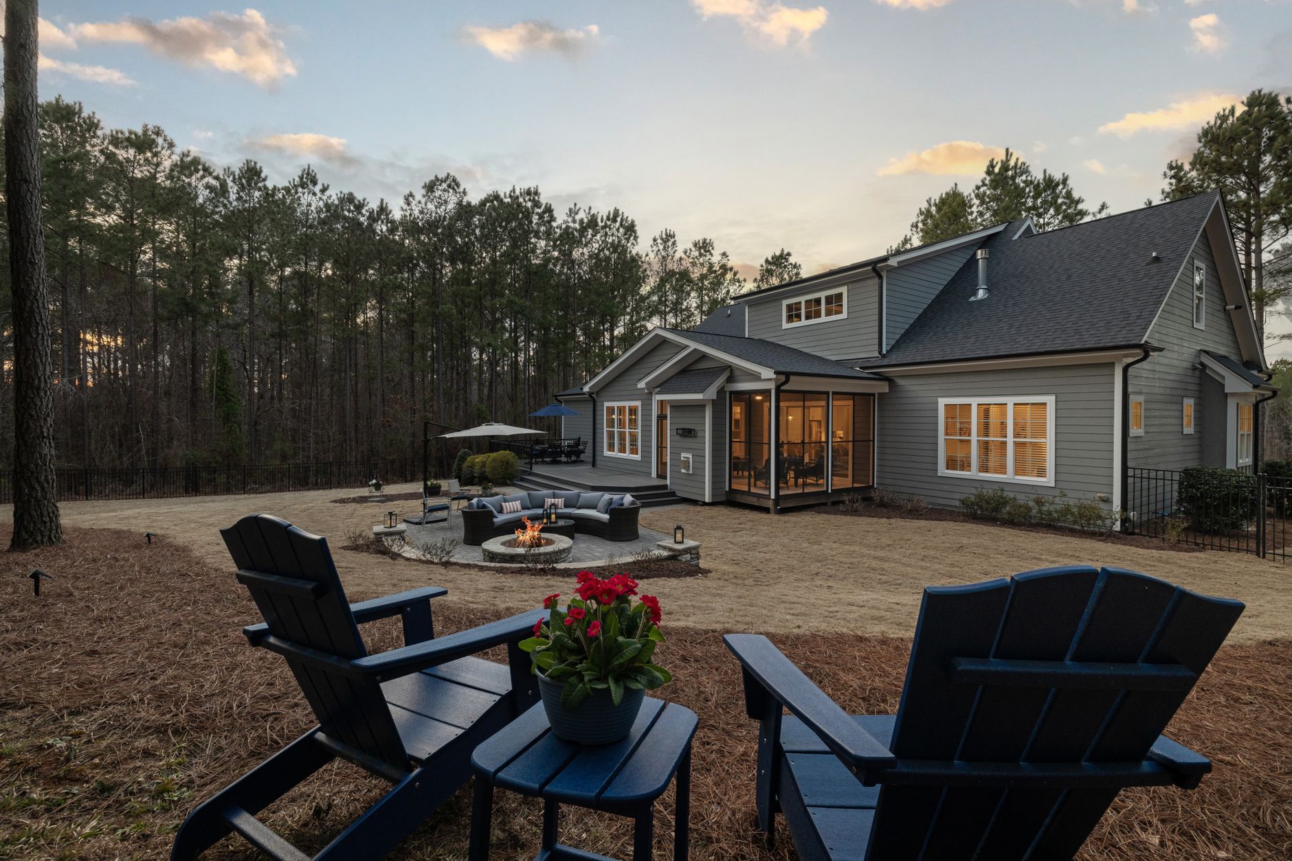 Backyard with a fire pit, seating area and Adirondack chairs at sunset